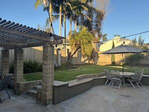 An outdoor patio with a pergola, seating area, and string lights. - Beautiful & Bright Talmadge Home (San Diego)