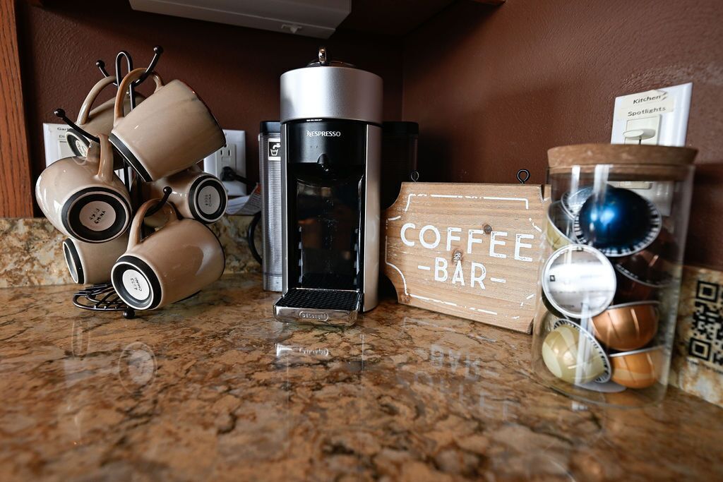 Una encimera de cocina con una cafetera, un cartel que dice 'Coffee Bar' y un tarro con granos de café.