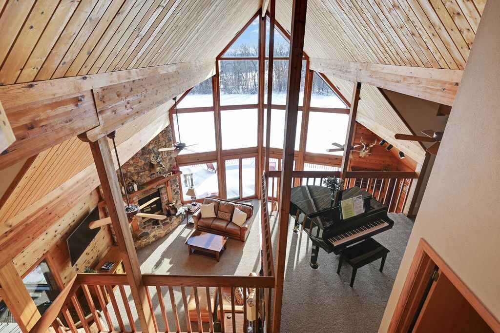 A high-ceilinged wooden interior with a piano, a fireplace, and a cozy seating area.