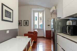 A compact kitchen with a refrigerator, microwave, and a dining area with a table and chairs. - GuestHost - Comfortable apartment located on the second floor, of six in total, of a building with a lift (NOT suitable for disabled people).In 60 m2 of space it comfortably accommodates three people, with a double bedroom and a single bedroom.Located in (Roma)