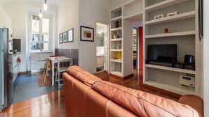 A modern living room with a sofa, a dining area, a kitchen, and a TV. - GuestHost - Comfortable apartment located on the second floor, of six in total, of a building with a lift (NOT suitable for disabled people).In 60 m2 of space it comfortably accommodates three people, with a double bedroom and a single bedroom.Located in (Roma)
