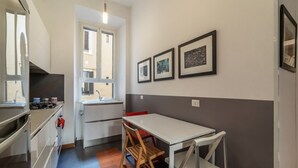 A compact kitchen with a dining area, a window, and framed pictures on the wall. - GuestHost - Comfortable apartment located on the second floor, of six in total, of a building with a lift (NOT suitable for disabled people).In 60 m2 of space it comfortably accommodates three people, with a double bedroom and a single bedroom.Located in (Roma)