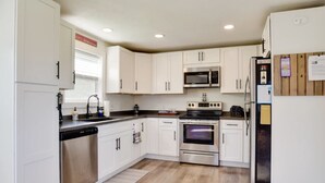 A compact kitchen with white cabinets, a microwave, a stove, and a refrigerator. - Finger Lakes House has private Pool, Fire Pit & Extra Amenities in Hammondsport  (Hammondsport)