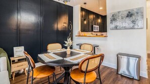 Un moderno comedor con una pared de acento negra, una araña y una cocina visible al fondo.