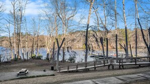 Un parque junto al lago con una mesa de picnic, un puente de madera y un muelle con barcos.
