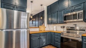 Una cocina moderna con electrodomésticos de acero inoxidable, armarios azul oscuro y encimeras de madera.