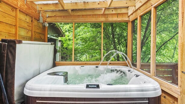 Un jacuzzi en una cabaña de madera con vista a un bosque.