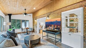 Una sala de estar moderna con chimenea, comedor y vista a un paisaje urbano a través de un ventanal amplio.