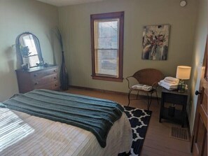 Ein Schlafzimmer mit Bett, Schminktisch, Stuhl, Lampe und Bildern.