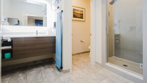 A modern bathroom with a glass shower enclosure, a sink with a mirror, and a towel rack.