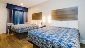 A hotel room with two beds, a wooden headboard, a nightstand, and a chair.