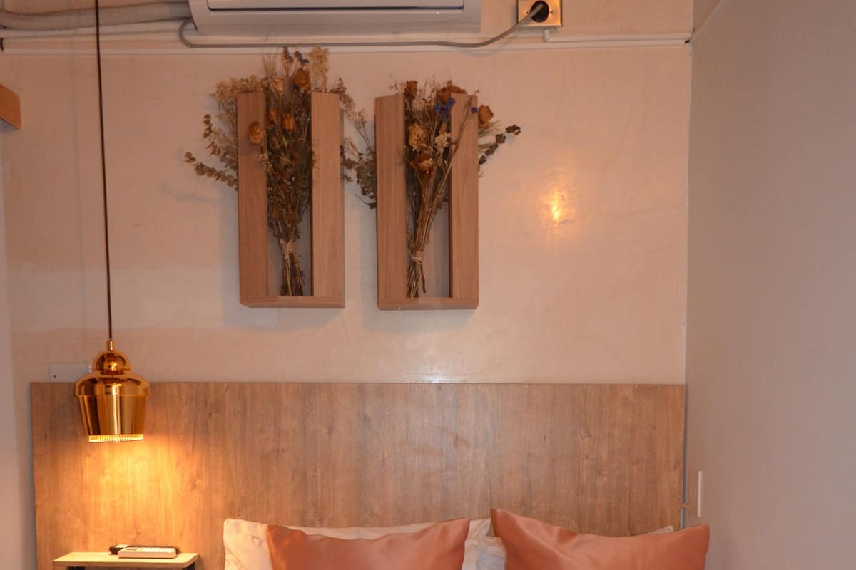 Ein Schlafzimmer mit Bett, Kissen, einem Nachttisch, einer Lampe und Wanddekorationen.