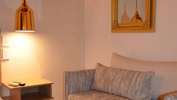 A room with a sofa, a small table with a lamp, and a mirror on the wall.
