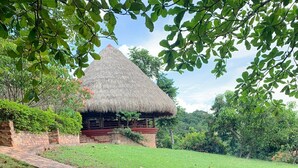 A traditional thatched-roof structure with a brick-built fire pit in the foreground.