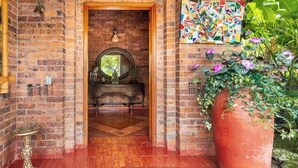 A brick entrance with a mirror, a potted plant, and a mosaic wall.