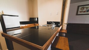 A kitchen with a black countertop, stainless steel sink, and wooden cabinets.