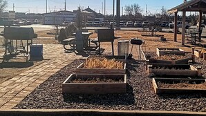 A parking lot with several cars, a gazebo, and a sign for Patriot Auto Sales.