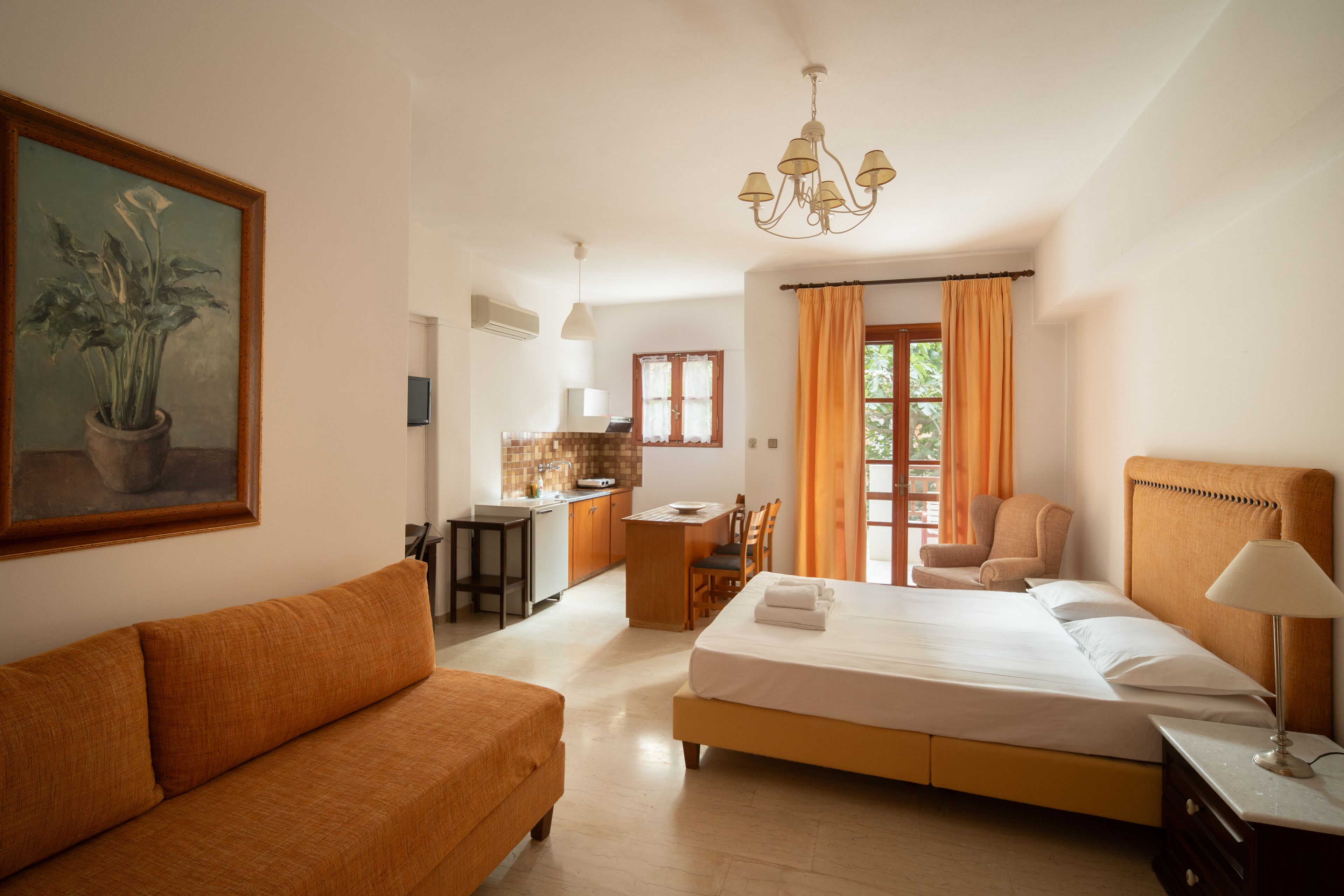 A hotel room with a bed, a sofa, a desk, and a chair.