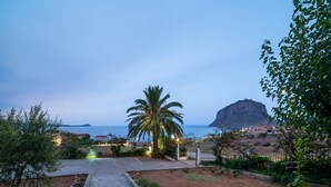 A pathway leading to a beach with a palm tree and a mountain in the background. - Alta Vista Studios (Monemvasia)