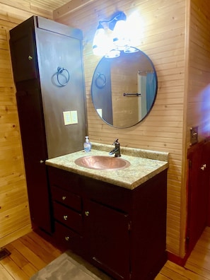 A wooden cabin bathroom with a sink, mirror, and cabinet. - 🌟Cozy Mountain Cabin with New Hot Tub🌟 (Mentone)