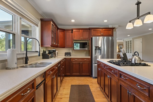 A modern kitchen with wooden cabinets, stainless steel appliances, and a large island.