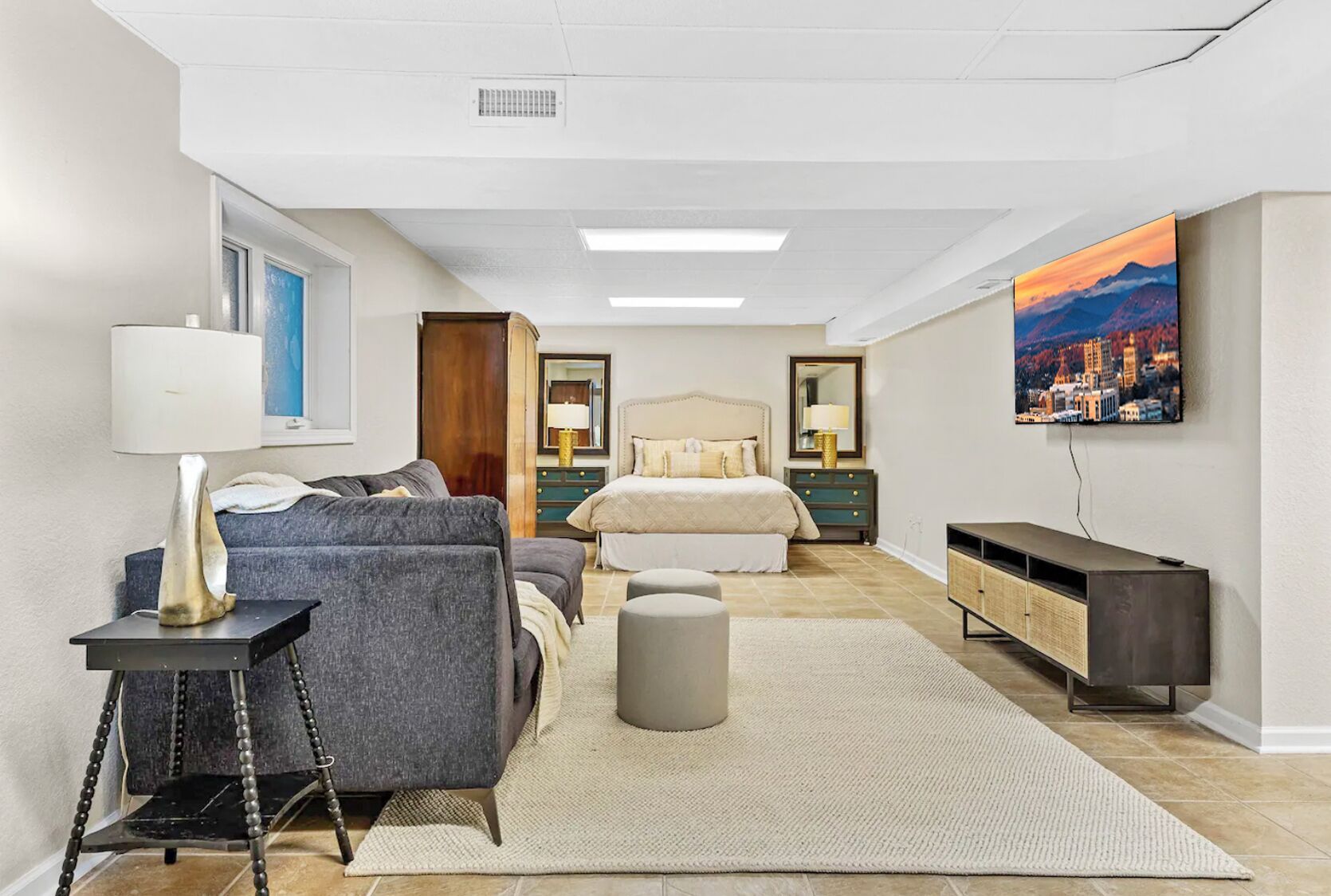 A modern bedroom with a bed, a sofa, a small table, and a TV.