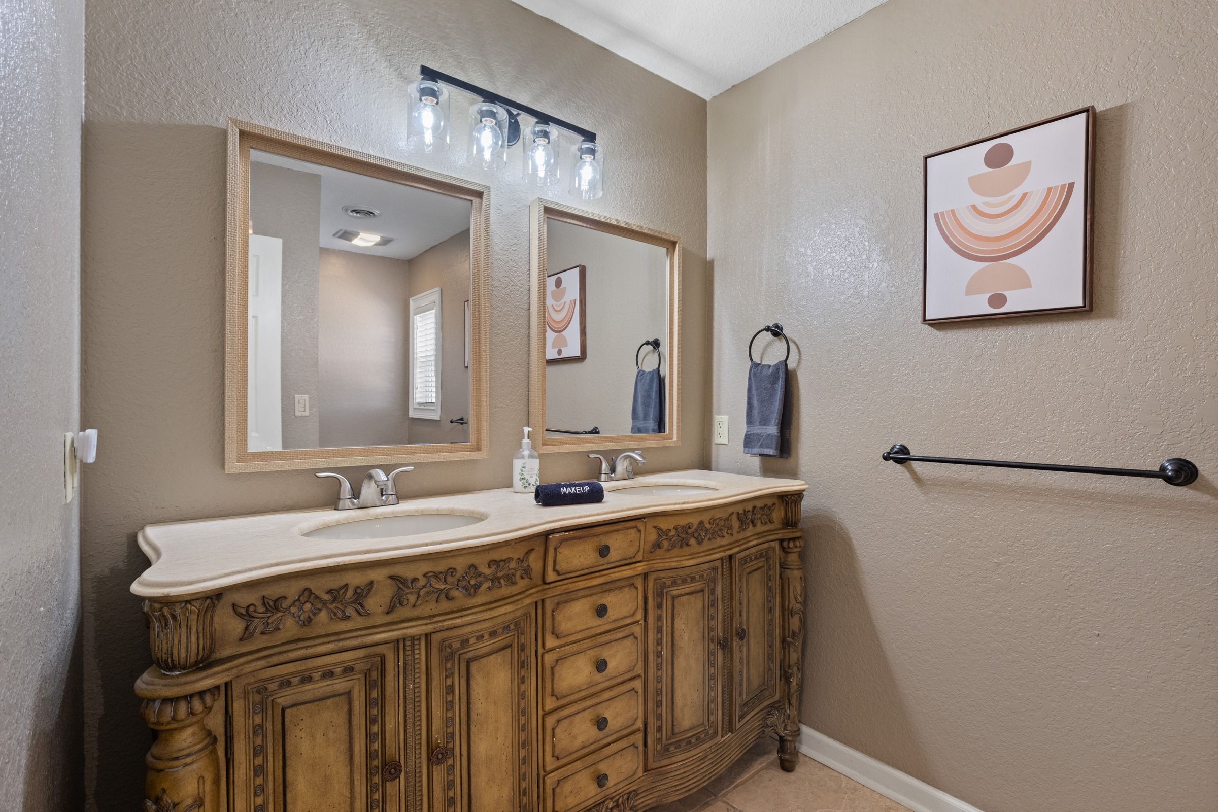 A bathroom with a double vanity, a large mirror, a towel rack, and a wall-mounted towel bar.