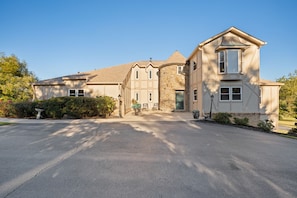 A two-story house with a stone facade, a large driveway, and a well-maintained lawn.