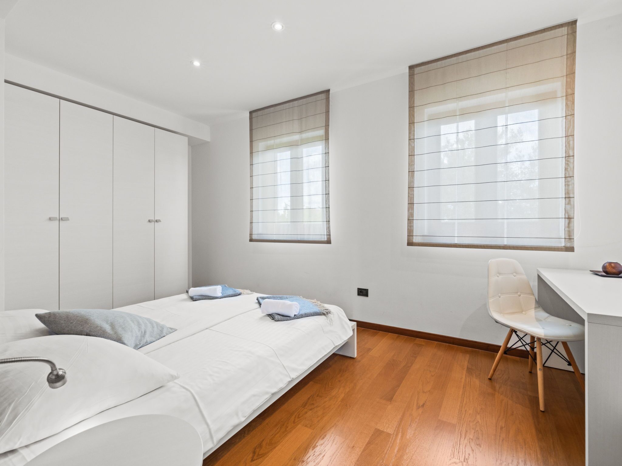 A modern bedroom with a bed, a desk, and a wardrobe.