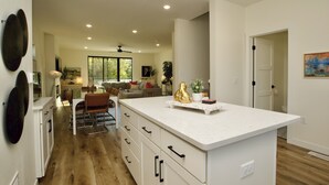 Una cocina amplia con una isla central, piso de madera y vistas a un área de estar.
