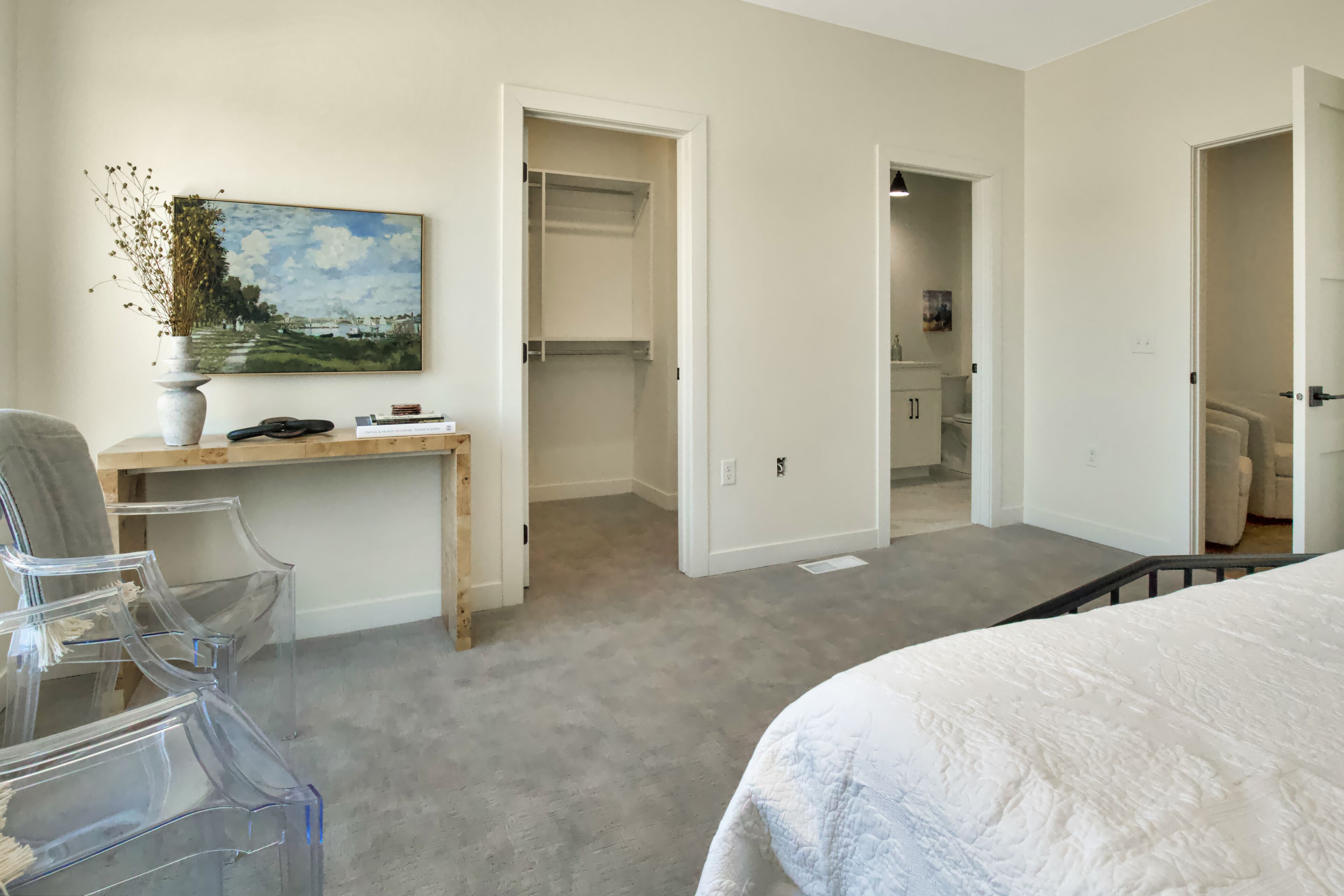 Een slaapkamer met een bed, een bureau met een vaas en een kledingkast.