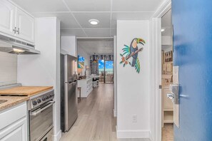 A modern kitchen with white cabinetry, a stainless steel refrigerator, and a wooden countertop.