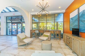 A lobby with a modern chandelier, seating area with chairs and a table, and a large window offering a view of the outside. - Ocean Reef 803 (Myrtle Beach)