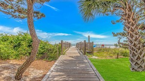 Una passerella di legno che conduce a una spiaggia sotto un cielo sereno.