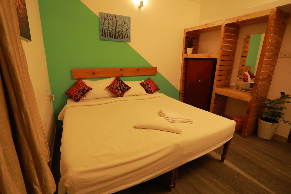 Uma cama bem arrumada com cabeceira de madeira, parede verde e um pequeno quadro em cima.
