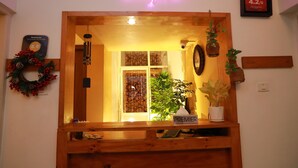 A reception area with a neon sign, a wooden desk, a plant labeled "Premier," and a framed certificate on the wall. - The WAVES by the Beach Inn (Kochi)