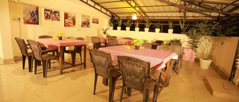 A dining area with tables covered in red and white checkered tablecloths, surrounded by chairs.