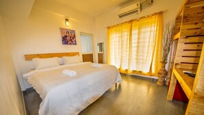 A hotel room with a large bed, a wooden headboard, a painting on the wall, a window with curtains, and a wooden bench. - The WAVES by the Beach Inn (Kochi)