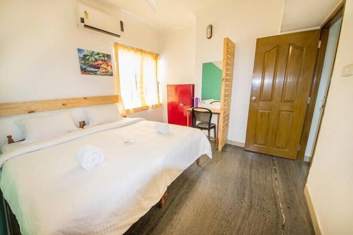Quarto com uma cama grande, uma escrivaninha, uma cadeira e uma porta.
