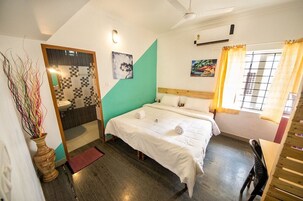 Un dormitorio con cama, cabecera de madera, ventana con cortinas, lavamanos y espejo.