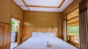 A wooden room with a bed, a nightstand, and a window with curtains.