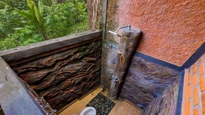 A bathroom with a rustic stone wall, a wooden bench, and a toilet.