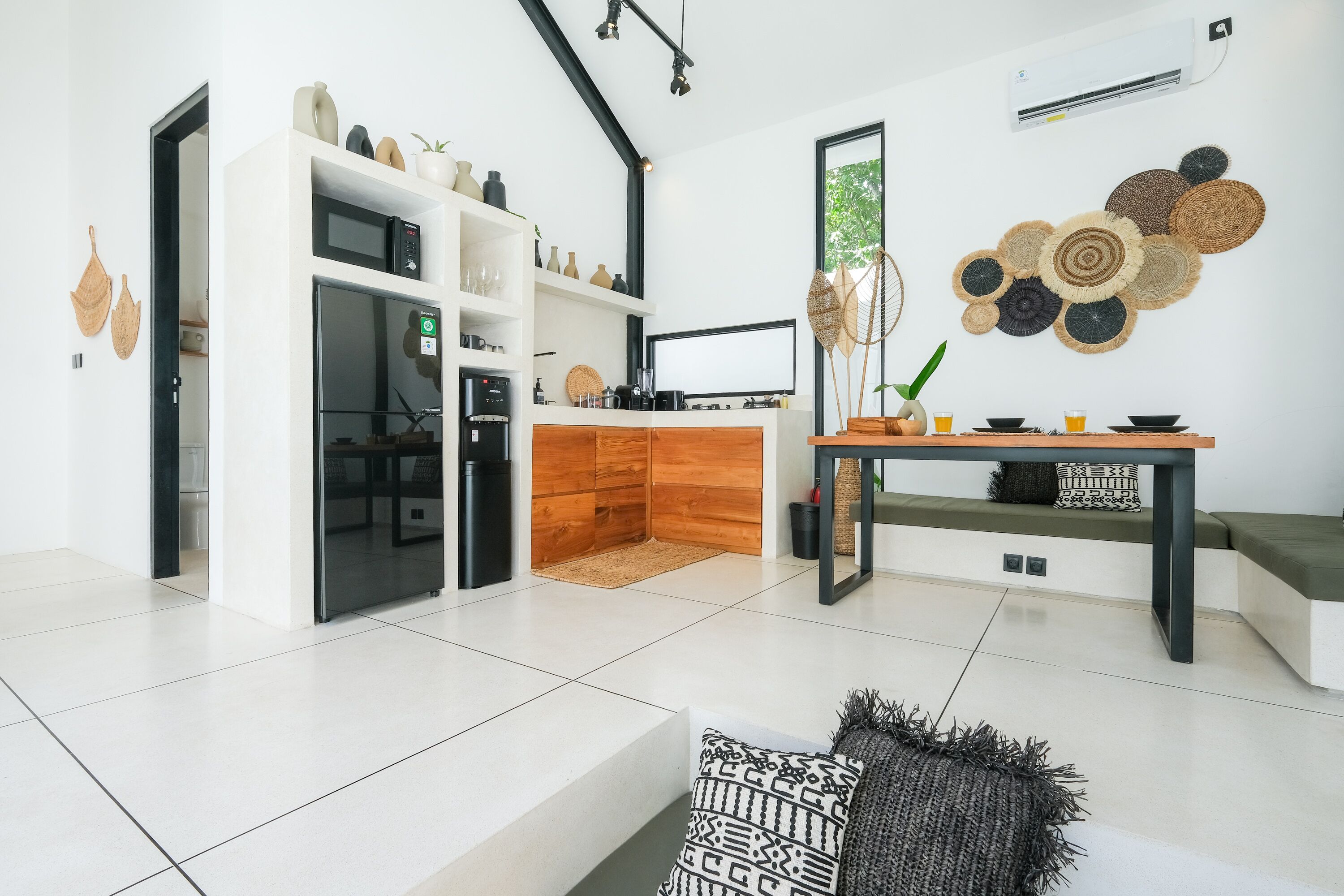 A modern kitchen with a microwave, stove, and wooden cabinets. There is a dining area with a table and chairs.