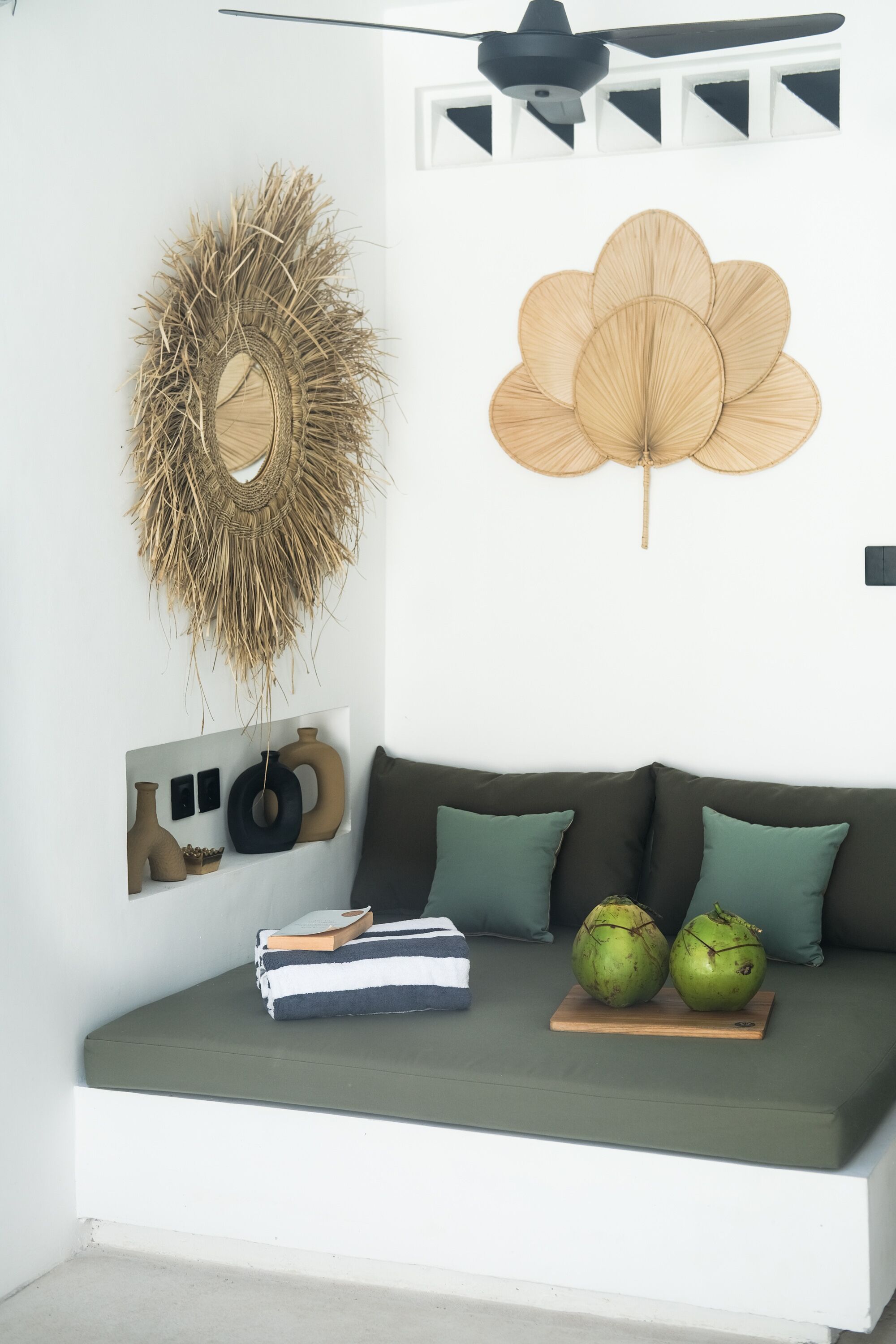 Una sala de estar moderna con un sofá verde, arte decorativo en la pared y un ventilador de techo.