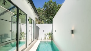 Ein moderner Poolbereich mit Glaswänden, klarem Wasser und Blumentöpfen.