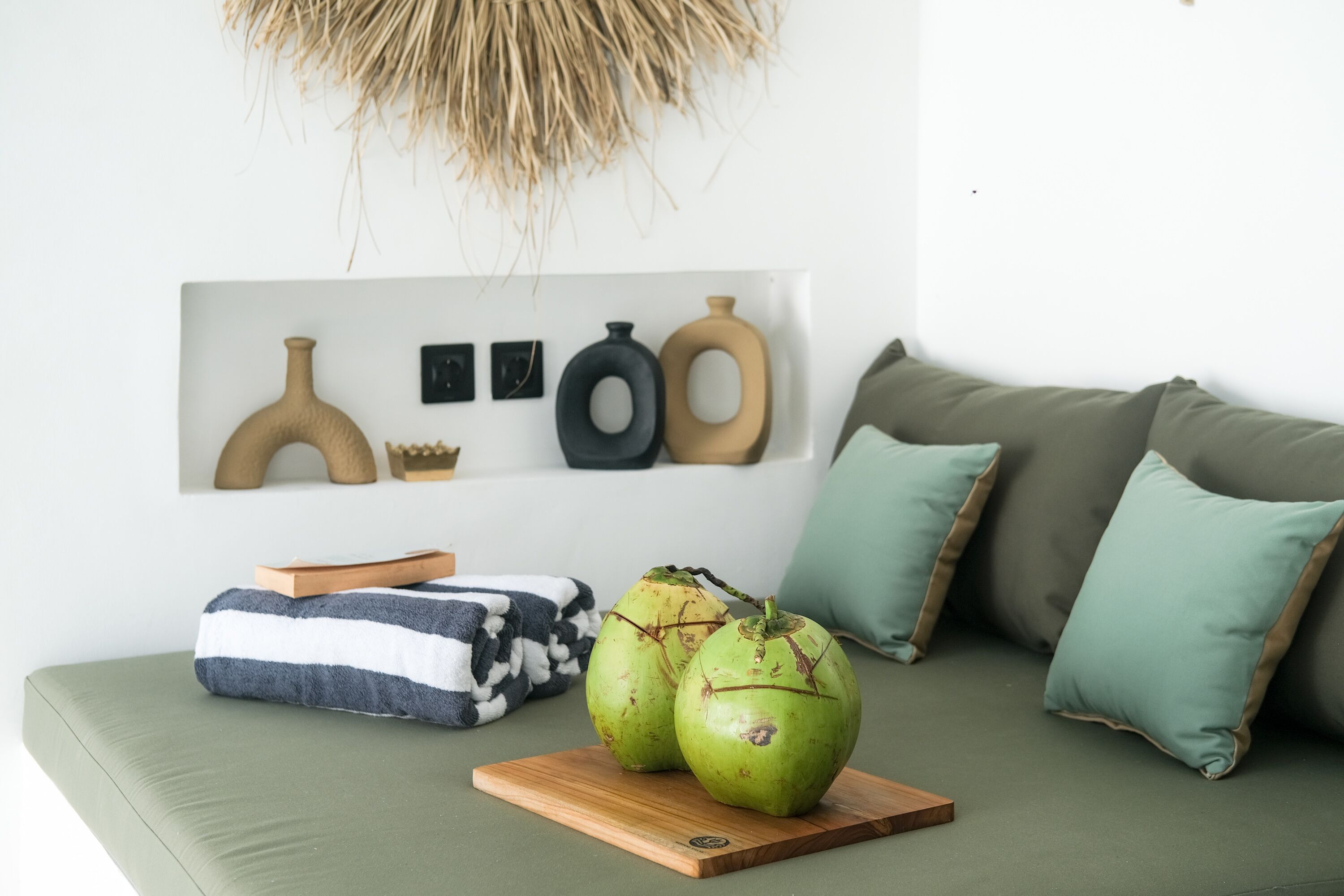 Una sala de estar moderna con un sofá verde, una mesa de centro de madera y jarrones decorativos en la pared.