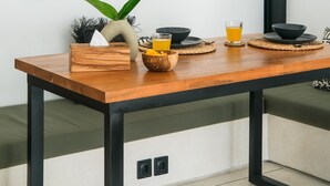 Ein Esstisch mit Untersetzer aus gewebtem Material, einer Vase mit Pflanze und zwei Gläsern Orangensaft.