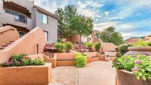 Une cour avec un banc, des jardinières fleuries et un escalier menant à un bâtiment.