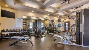 Une salle de sport équipée de divers appareils d’exercice, notamment des haltères, des tapis de course et des appareils de musculation.