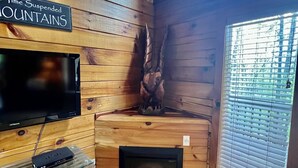 A wooden cabin interior with a mounted TV, a small heater, and a sign reading "Time Suspended Mountains". - New Hot Tub & Trailer Parking @ Cliff Eagle (Stanton)